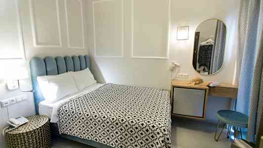 Et hotellrom med en seng, et nattbord og et speil. (AI-generert tekst)