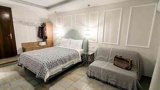 Et hotellrom med en seng, en sofaaktig sittemøbel og et garderobeskap. (AI-generert tekst)