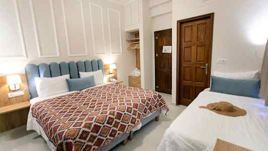 Et hotellrom med dobbeltseng, enkeltseng og treinnredning. (AI-generert tekst)