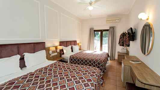 Hotellrom med to senger og et skrivebord, dekorert med geometrisk mønstrede sengetepper. (AI-generert tekst)