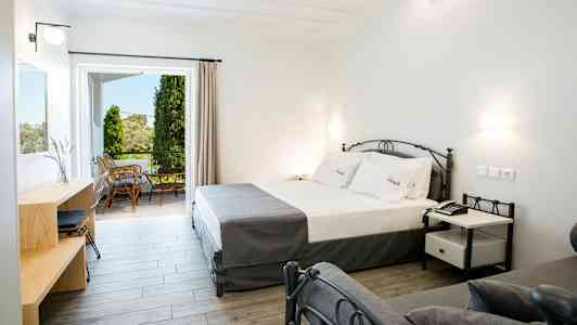 Moderne hotellrom med seng, skrivebord og utgang til møblert balkong. (AI-generert tekst)