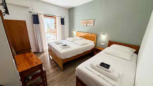Hotellrom med to enkeltsenger, et skrivebord og en balkong. (AI-generert tekst)
