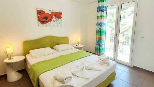 Et soverom med en dobbeltseng, grønt sengeteppe, håndklær og dekorasjoner. (AI-generert tekst)