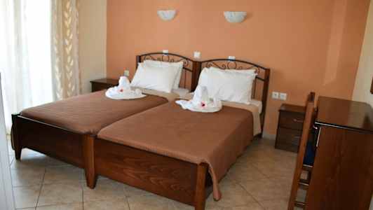 To enkeltsenger med hvitt sengetøy og dekorasjon, plassert i et rom med terrakotta veggfarge og mørke tremøbler. (AI-generert tekst)