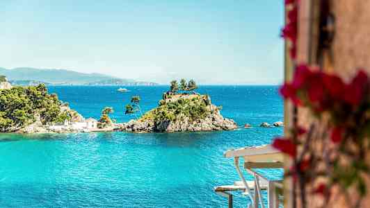 En liten øy med trær og et hus omgitt av blått vann. (AI-generert tekst)