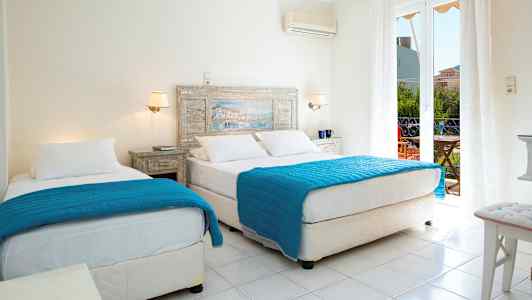 Et hotellrom med to senger med blå dyner og hvite laken. En glassdør leder til en balkong. (AI-generert tekst)