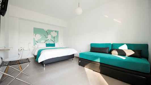 Et hotellrom med en seng og en sofa, innredet i lyse farger. (AI-generert tekst)