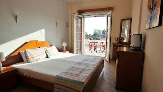 Et hotellrom med en dobbeltseng og en dør mot en balkong. (AI-generert tekst)