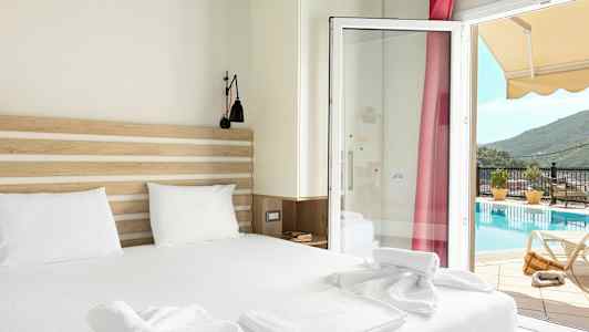 Et hotellrom med en dobbeltseng og utsikt mot et basseng gjennom en glassdør. (AI-generert tekst)