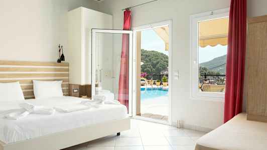 Hotellrom med seng, åpen glassdør og utsikt mot bassengområdet og omkringliggende grønt. (AI-generert tekst)