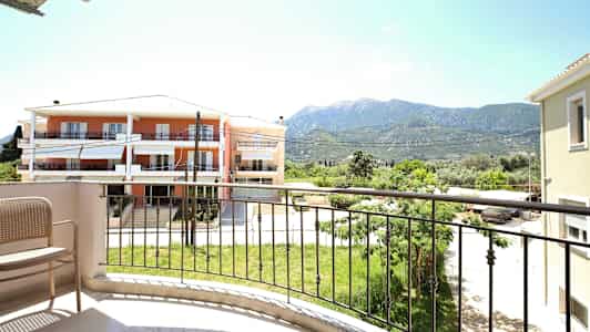 Utsikt fra en balkong med en stol, en gressplen og bygninger i bakgrunnen. (AI-generert tekst)