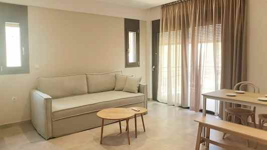 En sittegruppe med sofa, bord og spisebord. Vinduer med gardiner i bakgrunnen. (AI-generert tekst)