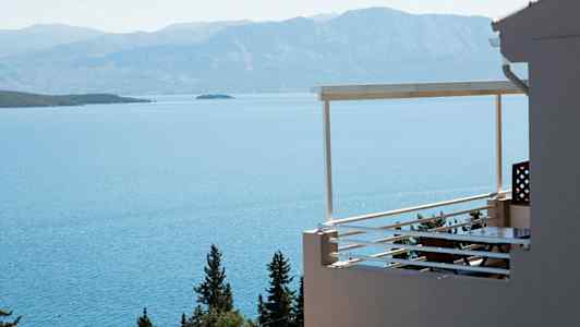 En balkong med utsikt over havet og omkringliggende fjell. (AI-generert tekst)