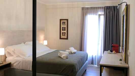 Moderne innredet soverom med dobbeltseng, nattbord og en skrivebordsflate med kaffemaskin. (AI-generert tekst)