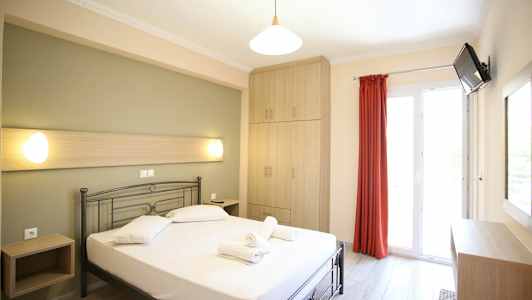 Et lyst hotellrom med en seng, skap og en balkongdør. (AI-generert tekst)