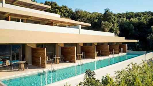 Utendørsbasseng ved hotellbygning med terrasse og avskjermede sittegrupper. (AI-generert tekst)