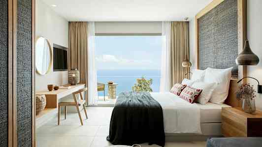 Moderne innredet hotellrom med havutsikt fra en stor glassdør. (AI-generert tekst)