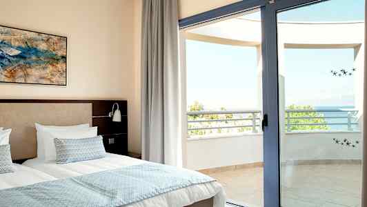 Bilde av et soverom med en dobbeltseng og en åpen balkongdør mot havutsikt. (AI-generert tekst)