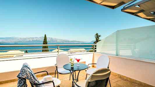 En terrasse med bord, stoler og utsikt over sjøen. (AI-generert tekst)