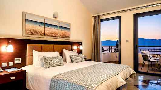 Rom med dobbeltseng, nattbord og havutsikt gjennom vinduet. (AI-generert tekst)