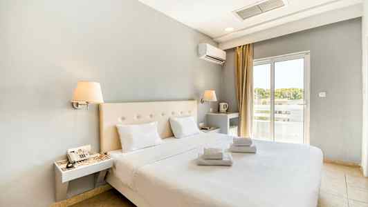 Moderne møblert hotellrom med dobbeltseng og hvite laken. Vindu med lysinnslipp. (AI-generert tekst)