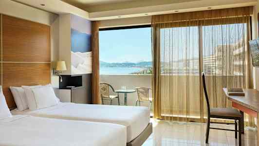 Rom med to enkeltsenger, en balkong med utsikt over havet og sittemøbler. (AI-generert tekst)