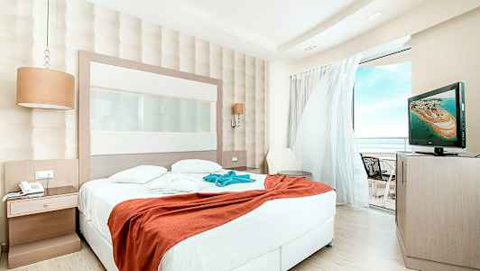 Hotellrom med stor seng og utsikt mot balkongen. (AI-generert tekst)