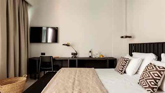 Et hotellrom med en seng, skrivebord og TV. (AI-generert tekst)