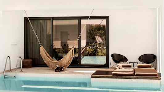 Bilde av et basseng med en hengekøye og solsenger ved kanten. (AI-generert tekst)