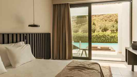 Et moderne hotellrom med en stor seng, beige gardiner og en glassdør som leder ut til en terrasse med basseng. Ute er det grønne omgivelser og en skråning. (AI-generert tekst)