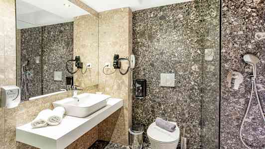 Et baderom med et speil, servant, toalett og dusj. (AI-generert tekst)