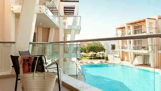 Utsikt fra balkong mot en moderne bygning og bassengområde. (AI-generert tekst)