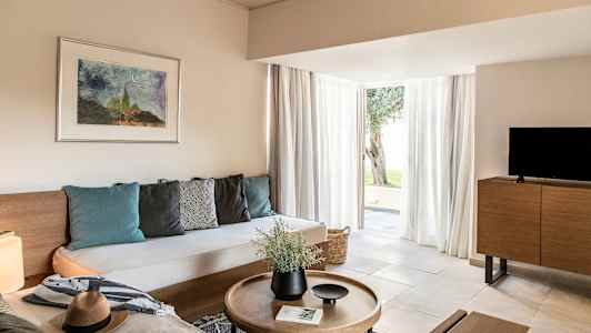 Et moderne innredet stue med en sofa, salongbord, TV og store glassdører som fører ut. (AI-generert tekst)