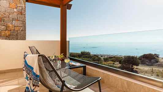 Terrasse med utsikt over havet, møbler og drikke på bordet. (AI-generert tekst)