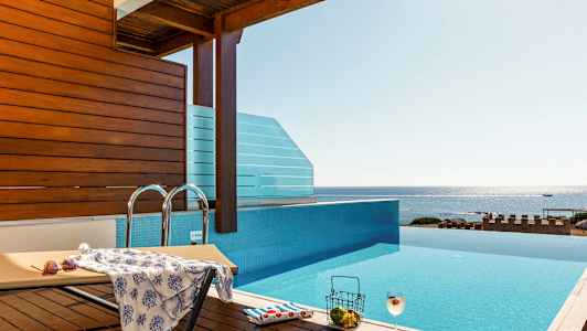 Et infinity-basseng med utsikt over havet, en solseng og en drink. (AI-generert tekst)