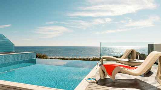 Solstoler ved et basseng med havutsikt. (AI-generert tekst)