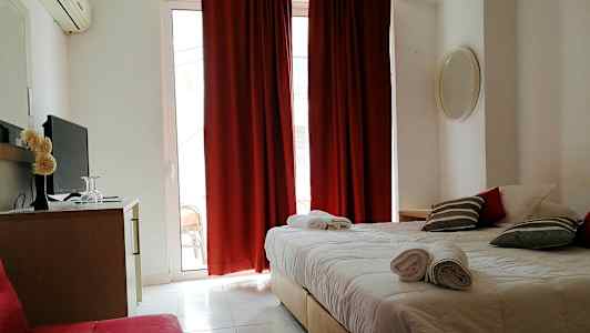 Et hotellrom med en dobbeltseng, røde gardiner og en TV på en kommode. (AI-generert tekst)