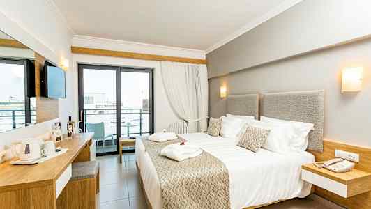 Moderne hotellrom med dobbeltseng, skrivebord og balkong. (AI-generert tekst)