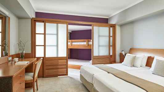 Bilde av et hotellrom med dobbeltseng, skrivebord og en sovealkove med køyeseng bak skyvedører av tre. (AI-generert tekst)