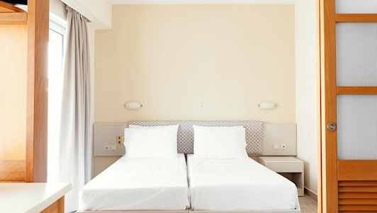 To enkeltsenger med hvitt sengetøy og nøytrale møbler. (AI-generert tekst)