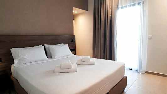 Et hotellrom med en dobbeltseng og hvite laken, samt foldede håndklær plassert på sengen. (AI-generert tekst)