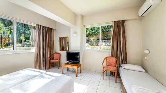 Et hotellrom med to senger, stoler, et bord med TV og store vinduer. (AI-generert tekst)