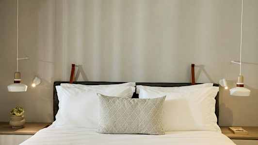 En seng med puter og opplyste lamper på begge sider. (AI-generert tekst)