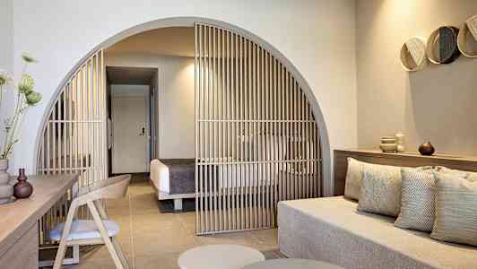 Moderne hotellrom med sittegruppe og avskjerming mot soveområde. (AI-generert tekst)