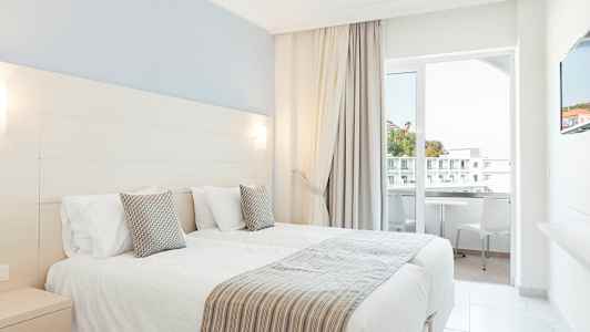 Hotellrom med to enkeltsenger og balkong. (AI-generert tekst)