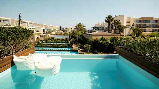 Basseng med utsikt over hotellbygninger og hager. (AI-generert tekst)