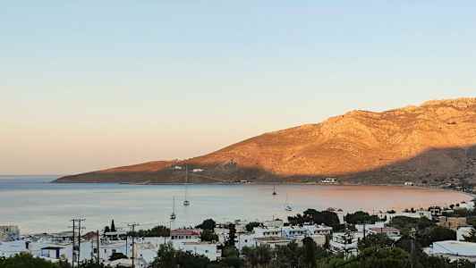 Strandby med seilbåter og fjell i bakgrunnen. (AI-generert tekst)