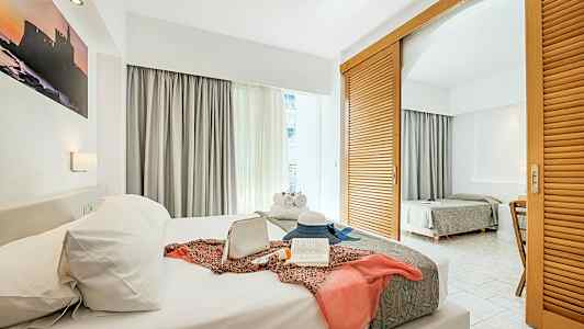 Et hotellrom med to senger, dekorert med personlige gjenstander på den fremste sengen. (AI-generert tekst)