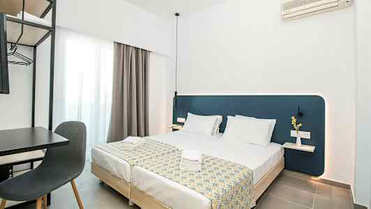 Moderne hotellrom med to oppredde enkeltsenger, skrivebord og stol samt veggmontert klimaanlegg. (AI-generert tekst)