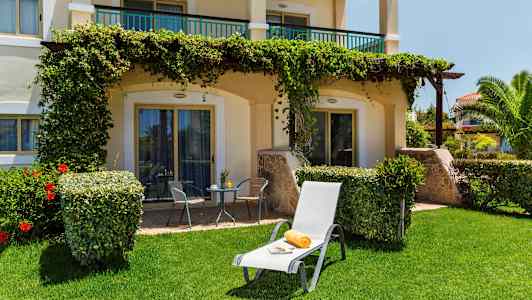 Bilde av en solseng med håndkle og avis på gressplen foran en terrasse. (AI-generert tekst)